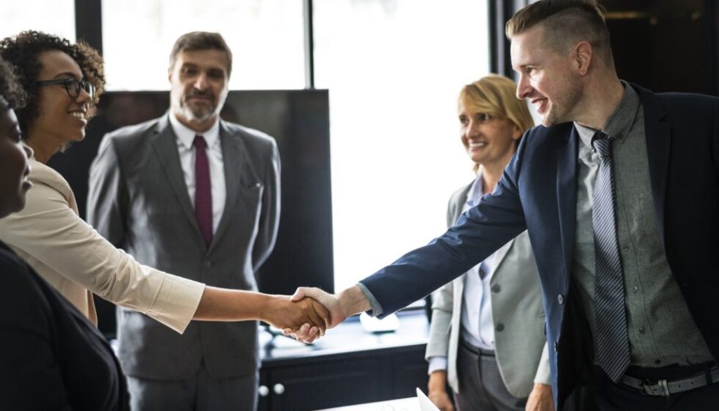 Diverse professionals engaging in a handshake during a business meeting, symbolizing collaboration and networking for the DISC Event focused on growth in home service industries.